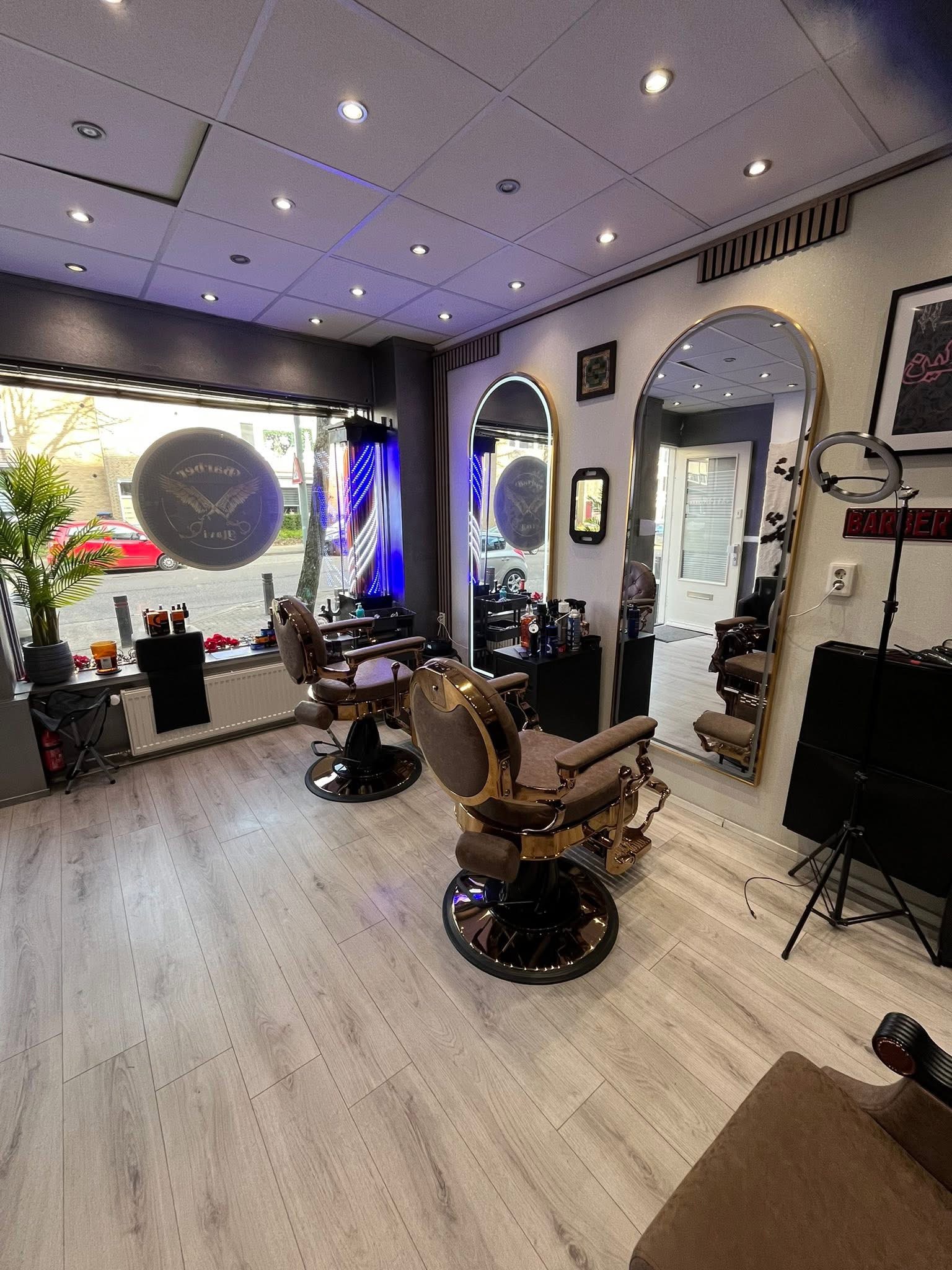 De zaak vanaf de achterkant: barberstoelen bij het raam met het logo, spiegels langs de wand