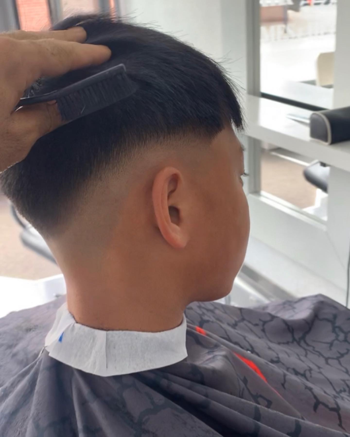 Korte fade in de nek, de kapper haalt de kam door het haar